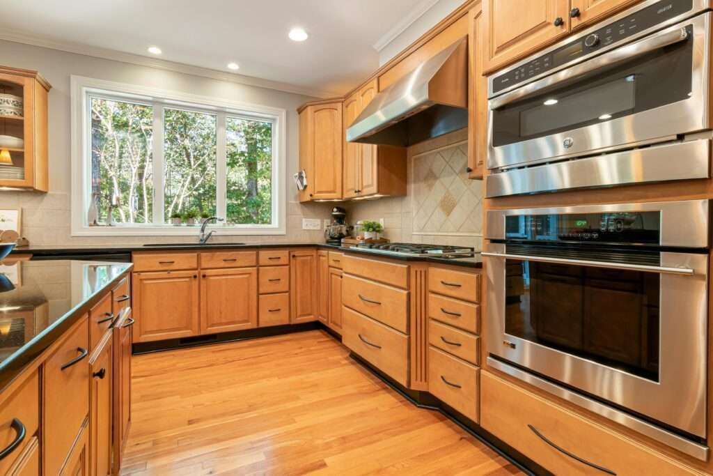 Professional kitchen renovation in Wolverhampton featuring custom wooden cabinetry, a modern kitchen island with a double oven, and a large window for natural lighting.