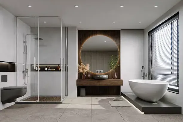 A contemporary luxury bathroom design Wolverhampton homeowners can inspire to, featuring a freestanding oval bathtub, a large round backlit mirror, wood slat wall paneling, a glass walk-in shower, and integrated ceiling spotlights.